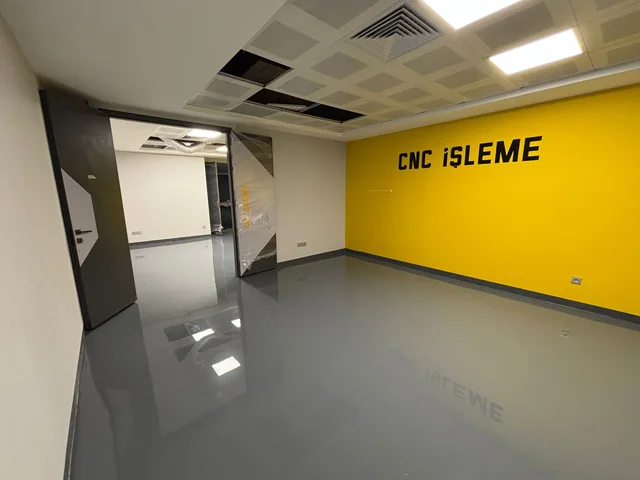 CNC çalışma alanında koyu gri parlak epoksi zemin